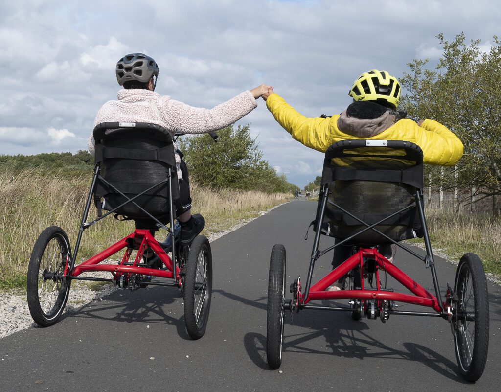 Two members of East Cumbria MS group riding adapted bikes at Watchtree Cycle Hire 