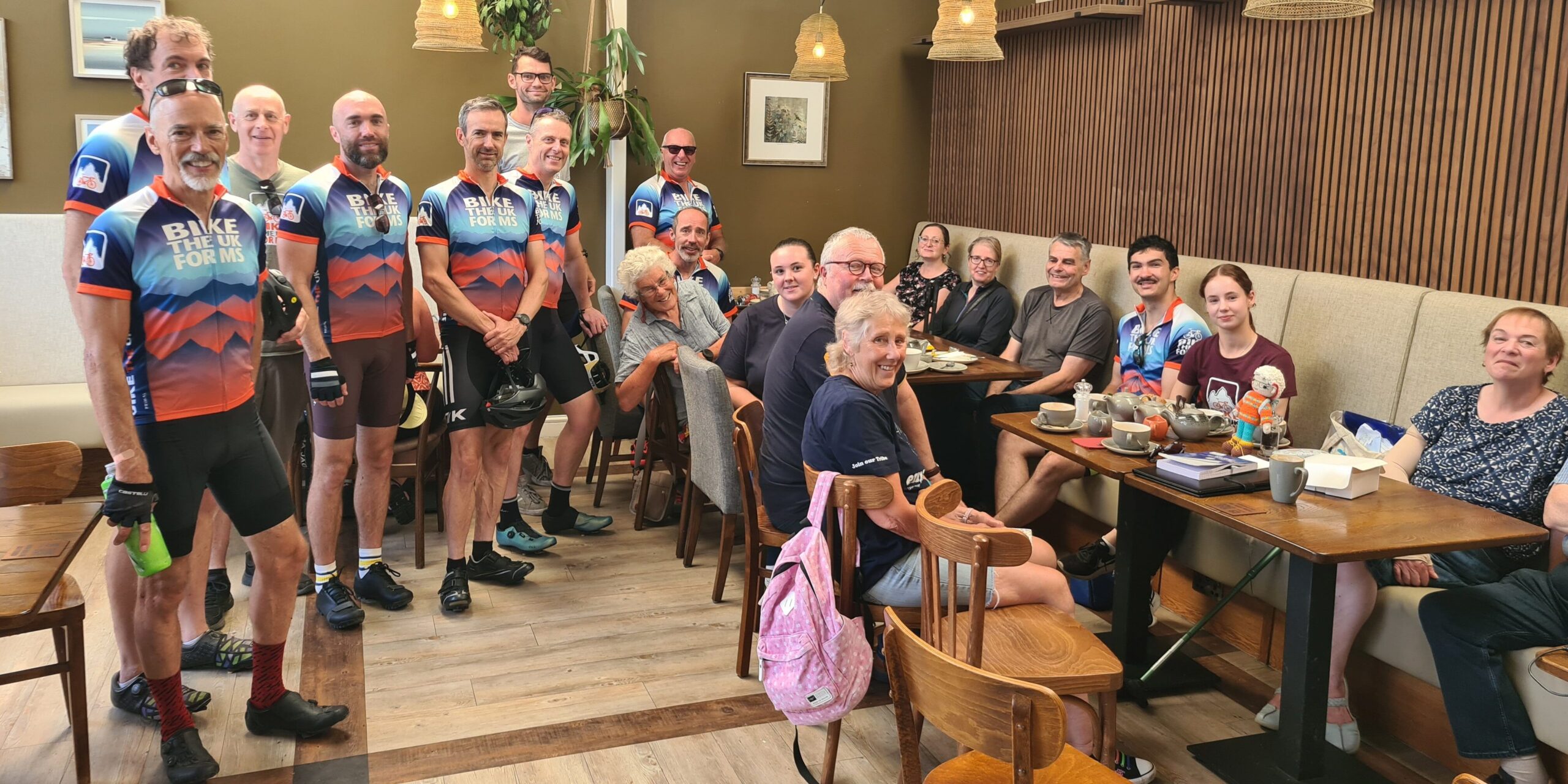 People at a table sat and stood around it smiling at the camera